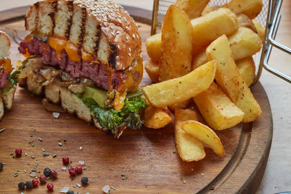 Delicious cheeseburger with cheddar and crispy fries on a wooden platter, perfect for a hearty meal.