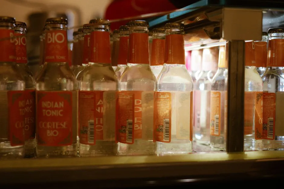 Glass bottles of organic tonic water neatly arranged in a refrigerator.