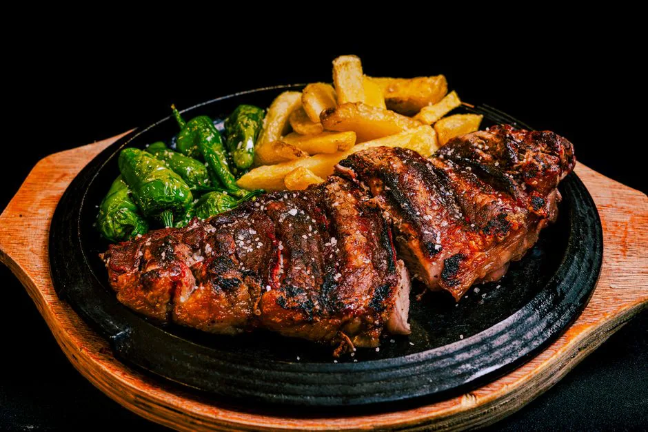 Delicious grilled steak served with fries and green peppers, a perfect dinner meal.