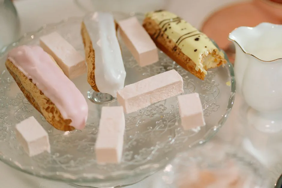 An elegant setup featuring eclairs and marshmallows on a decorative glass stand, perfect for dessert inspiration.