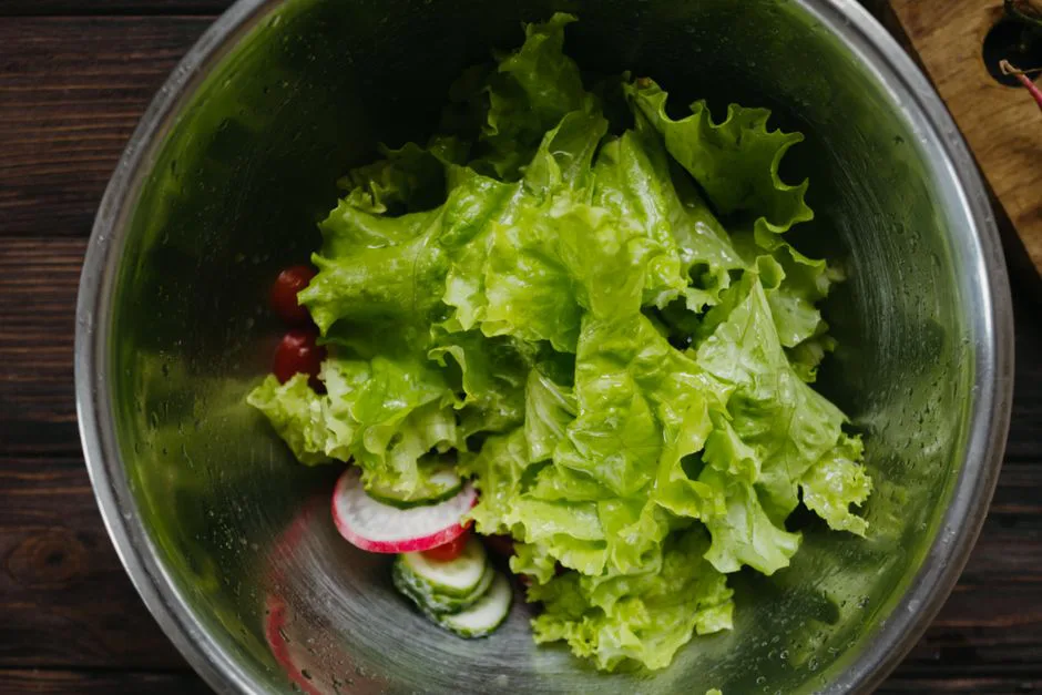 Top view of fresh salad ingredients in a stainless steel bowl ready for preparation.