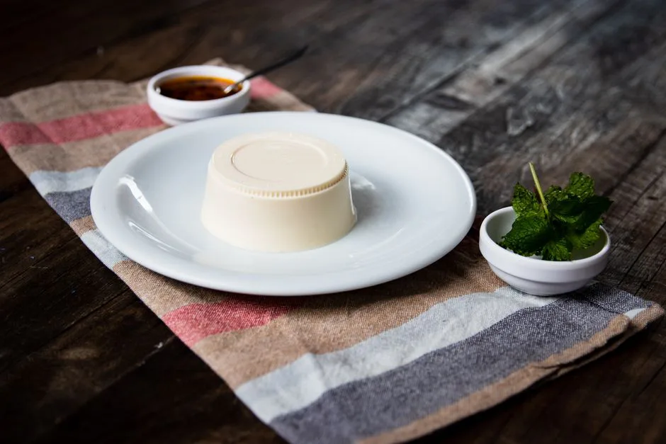 Delicious panna cotta served with fresh mint and sauce on a rustic table setting.