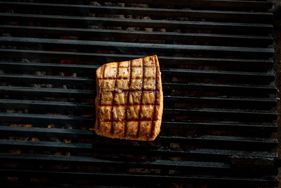 Close-up of a grilled salmon steak with grill marks on a barbecue.