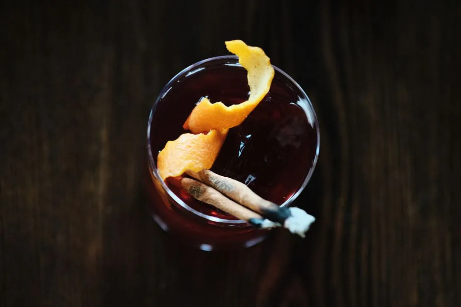 Top-down view of a cocktail garnished with orange peel and cinnamon stick, exuding sophistication.