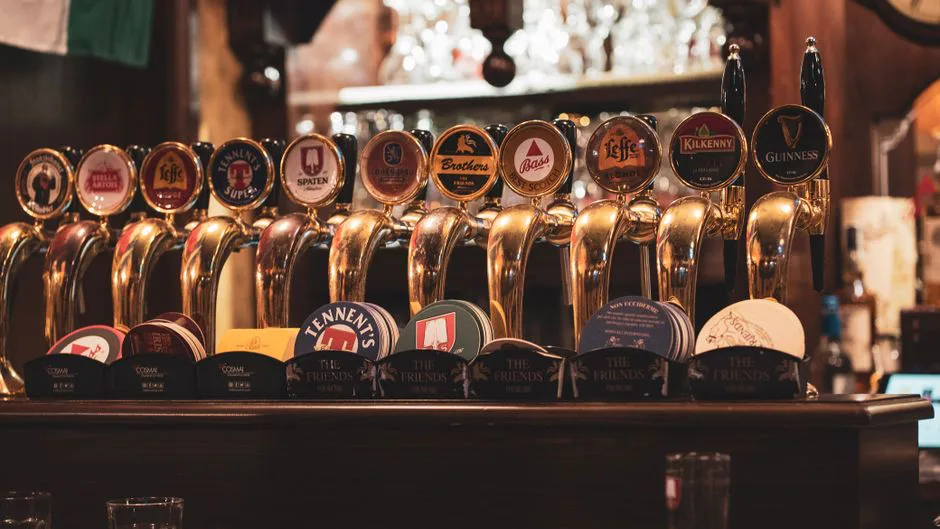 Close-up of multiple beer taps in a traditional bar setting in Milan, Italy.