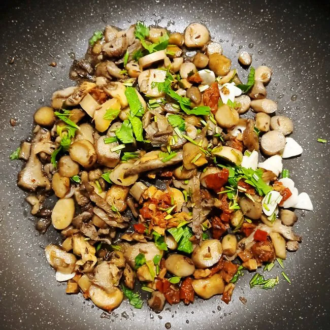 Close-up of a mix of sautéed mushrooms and herbs in a pan. Perfect for foodie content.