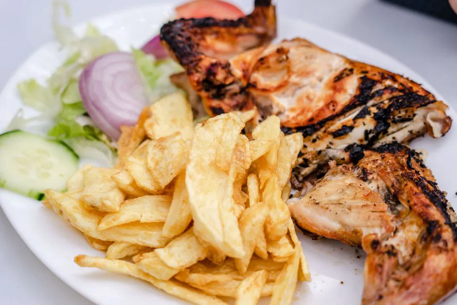 A delicious grilled chicken serving with crispy french fries and fresh salad.