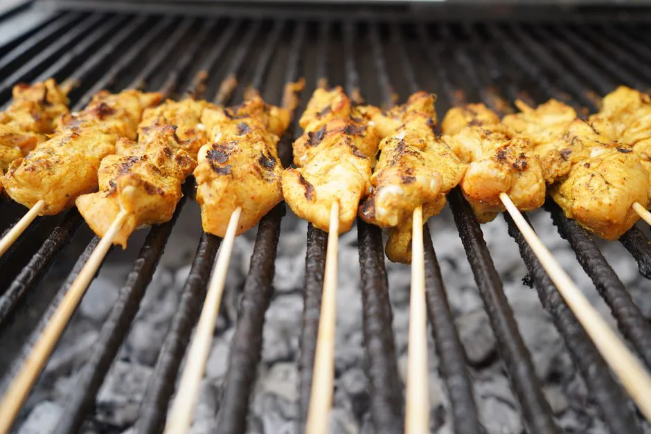 Close-up of delicious, juicy chicken skewers grilling over hot charcoal for a tasty meal.