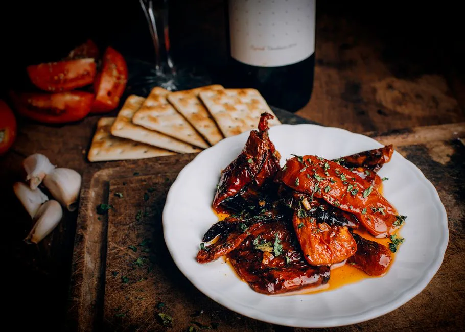 Delicious barbecued dish garnished with herbs, complemented by fresh tomatoes and crackers.