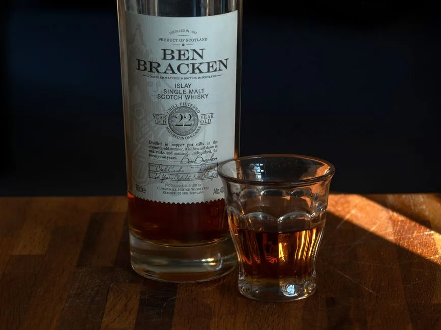 Close-up of Ben Bracken 22 Year Islay Single Malt Scotch Whisky with whisky glass on wooden surface.