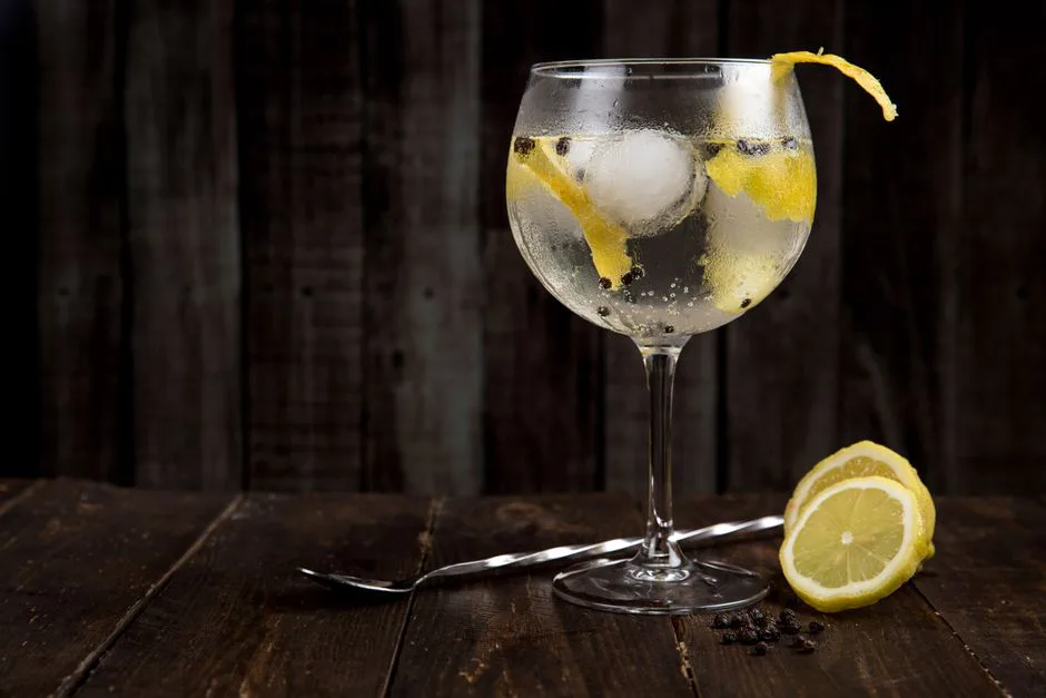 A close-up of a refreshing gin cocktail with lemon slices on a rustic wooden table, perfect for summer.