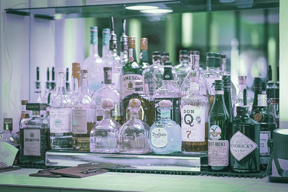 A diverse selection of liquor bottles displayed on a bar shelf, showcasing various brands and types.