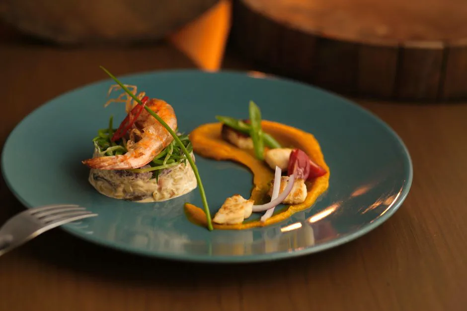 A gourmet shrimp appetizer elegantly plated with colorful vegetables and sauce.