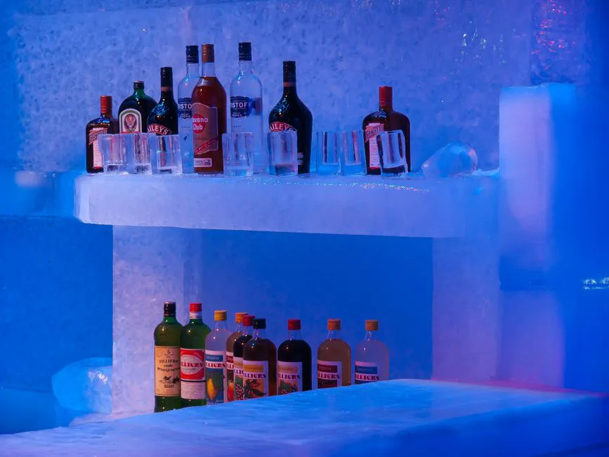 Vibrant display of liquor bottles and glasses on an ice bar in Brugge, Belgium.