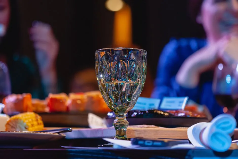 Close-up of a beautifully set dining table with a focus on a crystal wine glass, creating a warm and inviting atmosphere.