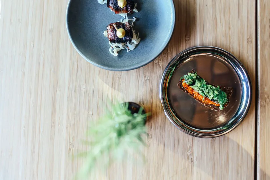 Elegant plating of gourmet dishes on wooden table, showcasing fine dining artistry.