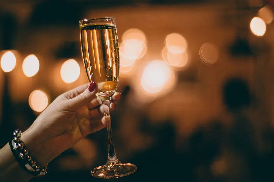 Crop faceless female with glass filled with alcoholic drink in hand in light cafe