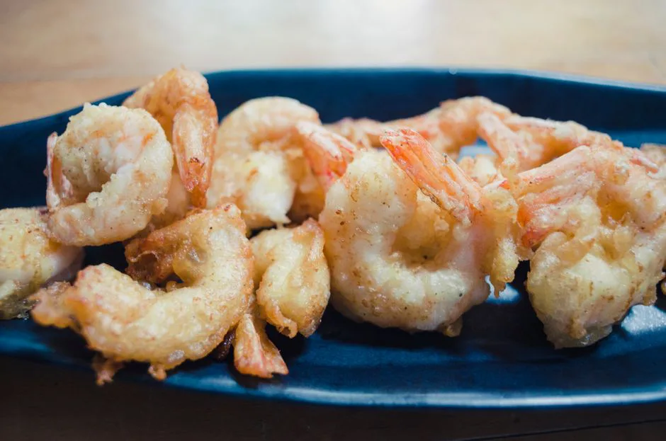 Tempting close-up of crispy fried shrimp served on a blue plate, perfect for seafood enthusiasts.