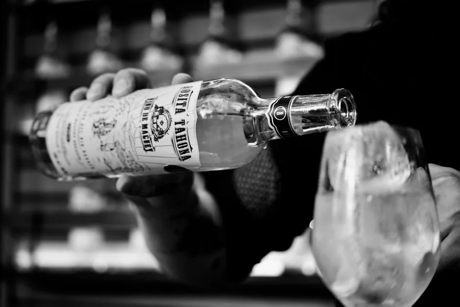 Black and white image of mezcal being poured in a glass with ice in Ciudad de México.