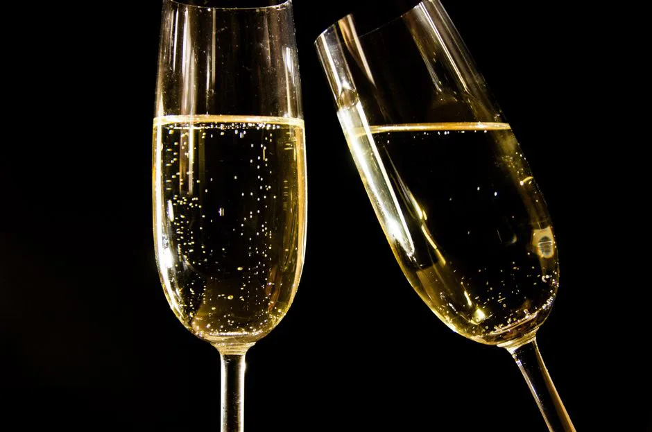 Close-up of champagne glasses with bubbles against a black background, perfect for celebrations.