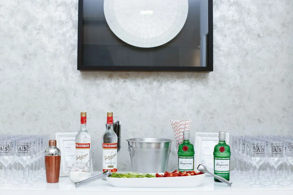 An upscale setup displaying vodka and gin bottles with glasses and garnishes on a white table.