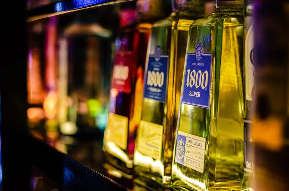 Colorful liquor bottles lined up on a bar shelf, highlighting tequila selection.