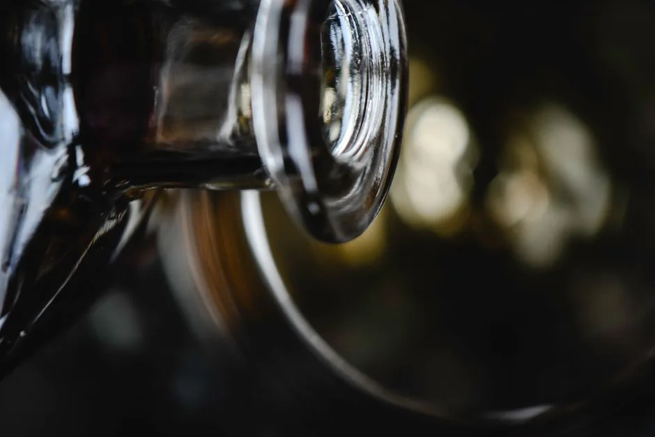 Artistic close-up of a glass bottle with dramatic lighting and bokeh effect.