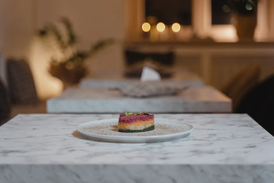 A beautifully presented gourmet dish on a marble table in a cozy restaurant setting with warm lighting.