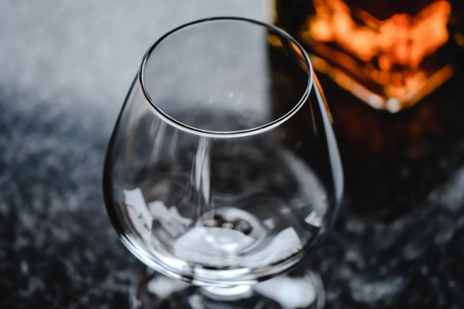 Elegant close-up of an empty snifter glass on a granite surface with a warm lighting effect.