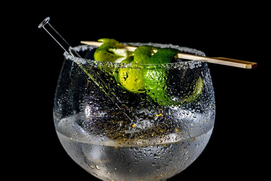 Close-up of a refreshing citrus cocktail with lime garnish on a black background.