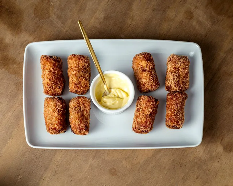 Tasty crispy chicken croquettes served on a plate with delicious dipping sauce.