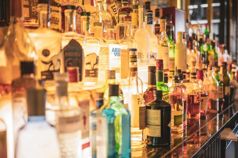 A close-up of various alcoholic beverage bottles displayed on a bar counter.